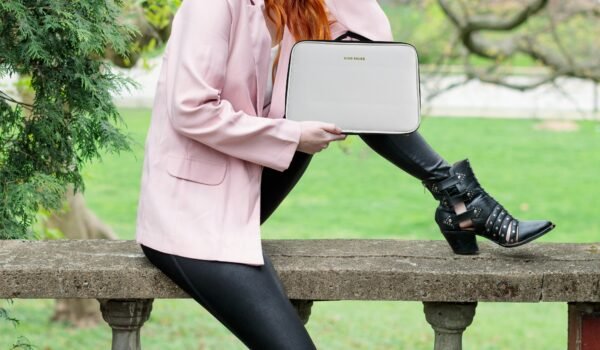 woman in pink blazer and black pants sitting on brown wooden bench